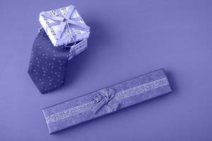 Gift box with a tie on a very peri background. Holiday gifts closeup with copy space photo