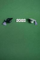 Graduation cap and numbers 2022 on green background, closeup with copy space. Medical education concept. photo