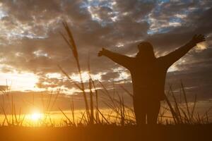 Silhouette of woman standing on field during sunset. photo