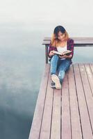 young beautiful hipster woman relaxing sitting on pier reading book. photo