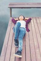 una joven hipster feliz se acostó en el lago del muelle, relajándose y disfrutando de la naturaleza. foto