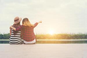 friendship,two women sit on the pier,Relaxing spending good time together. photo