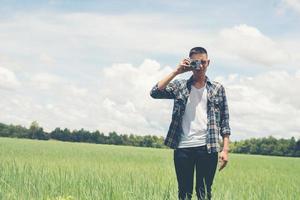 Young hipster handsome man photography standing shooting retro camera with nature enjoy and happy at grassland. photo