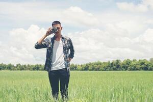 Young hipster handsome man photography standing shooting retro camera with nature enjoy and happy at grassland. photo