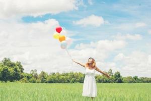 feliz joven hermosa mujer con globos en el campo de hierba disfruta con aire fresco.