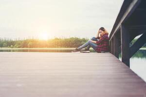 mujer hipster triste sentada en el muelle con tristeza. foto