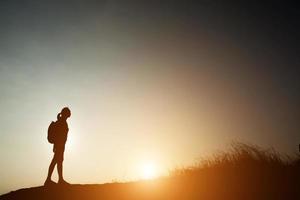 Silhouette of woman backpacking with sunset. photo
