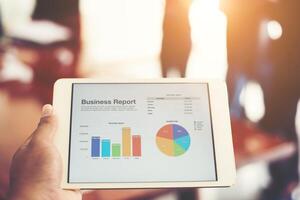 Business person hand holding financial statistics displayed on the tablet screen at office. photo