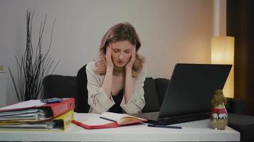 vermoeide vrouw, overweldigd door laptopwerk, heeft ernstige hoofdpijn.