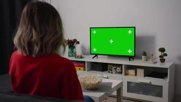 Woman watching Green Screen TV focused eating popcorn. video