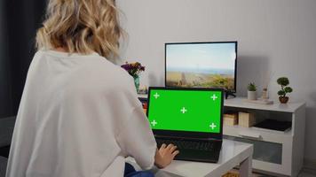 mujer caucásica realiza búsquedas en la web en una laptop con pantalla verde y clave de croma.