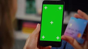 kvinna kund händer som håller kreditkort och smartphone med grön skärm. video