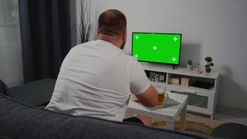 à la maison fan de football masculin assis sur un canapé en regardant la télévision à écran vert. video