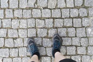 vista superior de los pies sobre los adoquines en zapatillas de deporte. foto