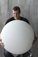 A man holding an inflatable ball on a gray background. photo