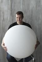 A man holding an inflatable ball on a gray background. photo