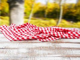 checkered tablecloth on old wooden table on blurred park background, holiday concept photo