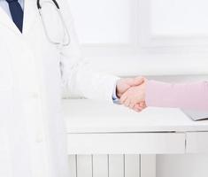 female hand of the doctor shakes the female arm of his patient in clinic, medical office. Healthcare concept, health insurance photo