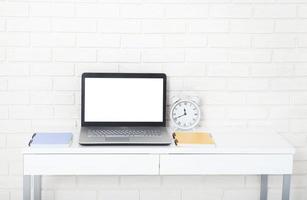 accesorios educativos en la mesa cerca de la pared de ladrillo. computadora vacía y pantalla móvil con lugar para texto. foto