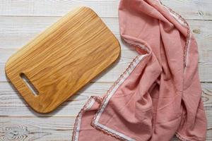 Cutting board and napkin on white wooden table. Empty tray. Mockup for design. Top view. photo