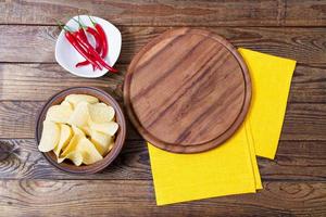 hot red pepper on plate,pizza desk,yellow napkin and potato chips on table, copy space,top view photo