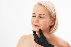 Botox injection concept Closeup portrait of a beautiful middle age woman and doctor hands isolated on white background. Collagen. Selective focus photo