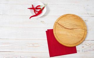 escritorio de corte vacío, pimiento picante y servilleta roja en la vista superior de la mesa de madera foto