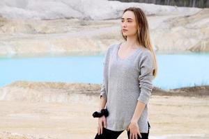 Beautiful teen woman posing at blue lake and yellow sand photo