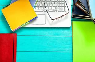 Notebooks with copy space and colorful accessories on blue wooden table. Top view photo