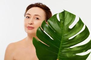 Beauty middle age woman macro face portrait. Spa and anti aging concept and leaf Isolated on white background. Plastic surgery and collagen face injections.Wrinkles and menopause. Mock up. Copy space. photo