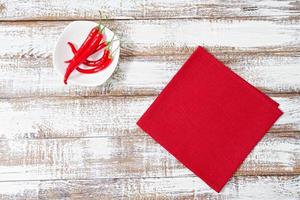 hot red pepper and paper napkin on old wooden table, holiday concept photo