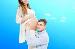 Portrait of young pair pending the kid isolated on blue background, Young attractive couple pregnant mother and happy father, Beautiful young couple expecting baby photo