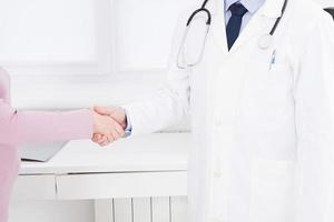 male hand of the doctor shakes the female arm of his patient in clinic, medical office. Healthcare concept, health insurance photo