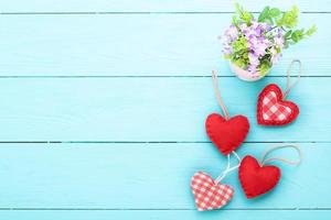 Vase of flowers and hearts on blue wooden background with copy space. photo