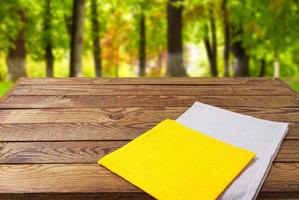 yellow grey napkins on wooden table on blurred park background photo