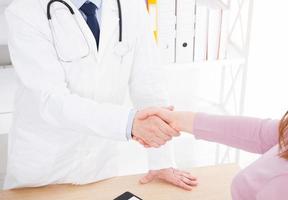 male hand of the doctor shakes the female arm of his patient in clinic, medical office. Healthcare concept, health insurance photo