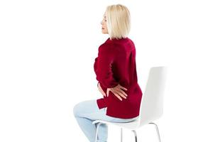 Woman female back ache, back pain - middle age woman sitting on chair and massaging back pain