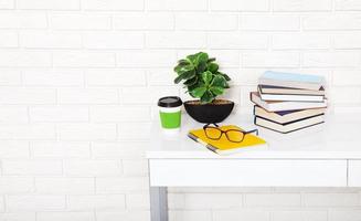 Workplace with cup of coffee and education stuff in the room. Brick wall. Copy space and selective focus photo