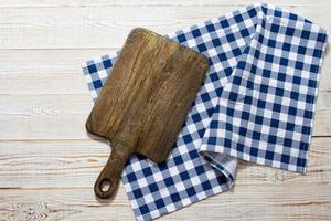 Dark old wooden cutting board and tablecloth on table, top view photo