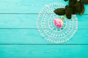 Pink rose and lace napkin on blue wooden background. Top view and copy space. Mothers day photo