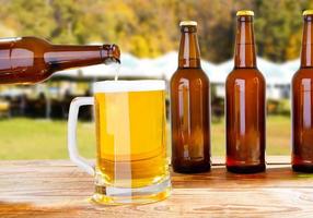 botellas de cerveza y copa de cerveza en el fondo borroso del patio de verano foto