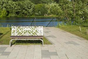 Bench near the river with a concrete path. photo