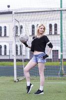 Beautiful blonde with a ball at the football goal. photo