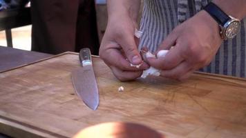 cuisinier coupé de fines tranches d'ail avec un couteau sur la coupe