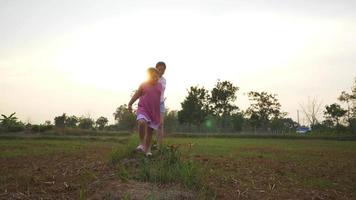 menina gorda asiática e mãe correndo no campo, aproveite as férias, correndo para a câmera na grama no grande parque com muitas árvores e luz solar. bela natureza no conceito de noite
