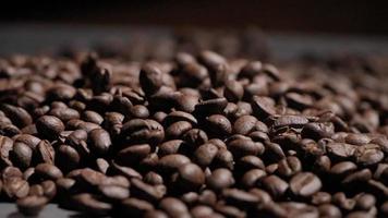 Slow-motion shot van koffieboon vallen op zwarte achtergrond, close-up macro op geroosterde arabica koffiebonen zaad