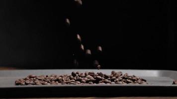 slow motion shot of coffee bean falling on black background, closeup macro on roasted arabica coffee beans seed video