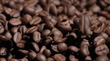 tiro em câmera lenta do grão de café caindo sobre fundo preto, macro closeup na semente de grãos de café arábica torrado video