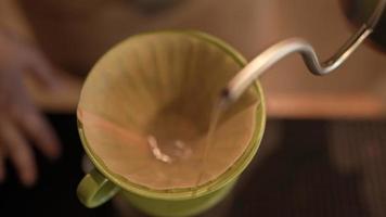 Slow-motion-bild av barista som gör en varm kaffe med filterdroppande vattenprocess, hemlagat kaffe på morgonen hemma eller café, vintage handbryggande vatten över rostade kaffebönor video