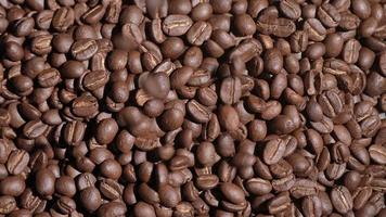 Zeitlupenaufnahme einer Kaffeebohne, die auf schwarzen Hintergrund fällt, Nahaufnahmemakro auf gerösteten Arabica-Kaffeebohnensamen